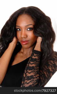 A lovely African American woman in a black blouse standingin the studio holding her hands on her head, isolated for white background.