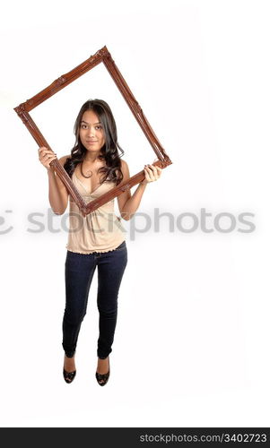 A lovely Asian woman in jeans and a beige blouse holding up a pictureframe for her head, standing in the studio for white background.