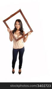 A lovely Asian woman in jeans and a beige blouse holding up a pictureframe for her head, standing in the studio for white background.