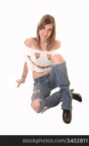 A lovely blond teenager girl sitting on the floor in a ripped jeans and anshort blouse with a gold face on, for white background.