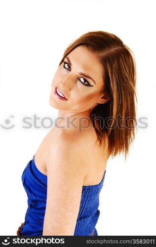 A lovely brunette woman in a blue top, looking into the camera forwhite background standing from the site.