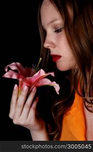 A lovely closeup picture of a beautiful teenager girl holding a pink lilyisolated for black background.
