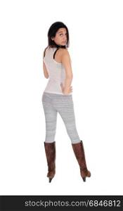 A lovely Hispanic woman standing from the back in gray leggings andbrown boots, isolated for white background.. Young woman standing from back.