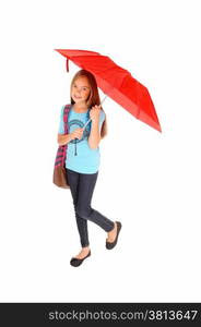 A lovely little girl in jeans standing isolated for white background holdinga red umbrella and her backpack over her shoulder.