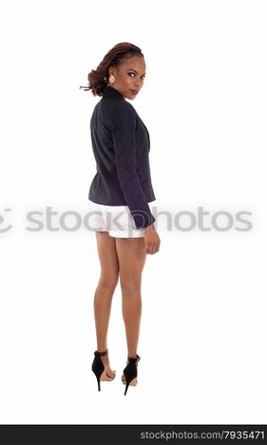 A lovely slim young African American woman in a dark blue jacket and whiteshorts, standing from back, isolated for white background.