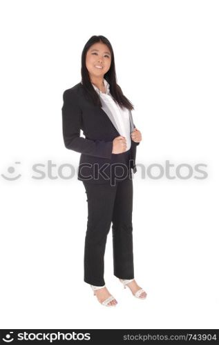 A lovely smiling Asian business woman standing in a portrait image in a black business suit and white blouse, isolated for white background