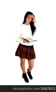 A lovely teenage girl in her school uniform with a book open and thinking,standing for white background with her long black hair.