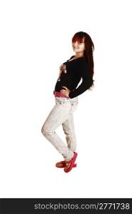 A lovely teenager girl with bright red hair, a black sweater and gray jeansstanding for white background.