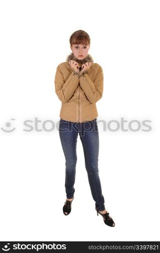 A lovely teenager in jeans and a brown jacket standing in the studio forwhite background.