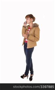 A lovely teenager in jeans and a brown jacket standing in the studio forwhite background.