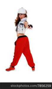 A lovely woman in red pants, jeans jacket and a hat standing in profile andpointing with her finger, isolated on white background.