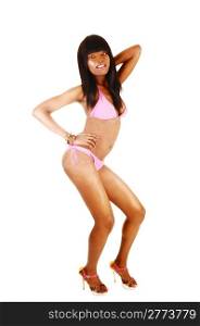 A lovely young African American woman in a pink bikini and high heelsdancing in the studio for white background.