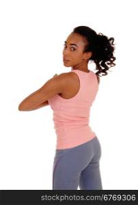A lovely young african american woman standing from back in pink t-shirtand gray pants, looking over her shoulder, isolated foe white background.