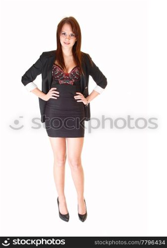 A lovely young businesswoman in a short skirt and dark gray blazer andhigh heels standing for white background in the studio.