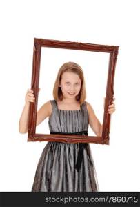 A lovely young girl in a grey dress holding a picture frame in frontof her, isolated on white background.