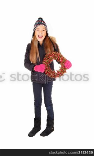A lovely young girl in a jacket, knitted hat and mittens holding an advents wreath, isolated for white background.