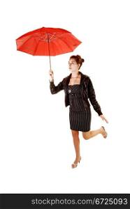 A lovely young woman in a black dress and brown leather jacket and highheels standing on one leg for white background holding up a red umbrella.