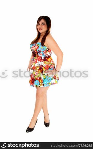 A lovely young woman in a colourful short summer dress standing in profile,isolated for white background.