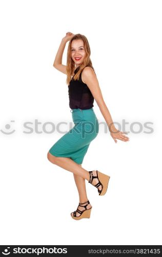 A lovely young woman in a green skirt a black blouse dancing in the studioisolated on white background.