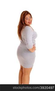A lovely young woman in a tight gray dress standing in profile isolatedfor white background, with her hands on the hip.