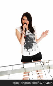 A lovely young woman in shorts, standing for white background, singing andholding her microphone.