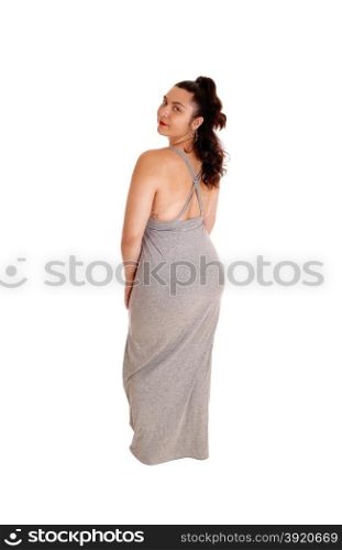 A lovely young woman standing in profile in a gray dress, isolatedfor white background, looking over her shoulder.