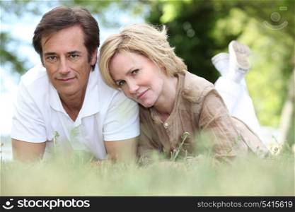 A loving couple lying on the grass
