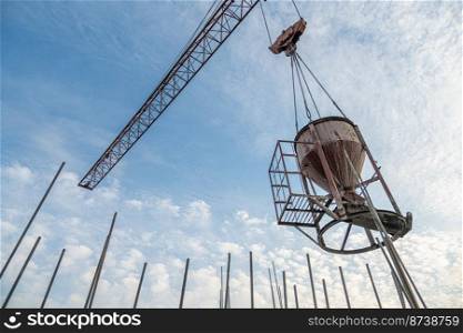 A low angle shot of a crane with equipment on a construction site near a new building infrastructure. Low angle shot of a crane with equipment on a construction site near a new building infrastructure