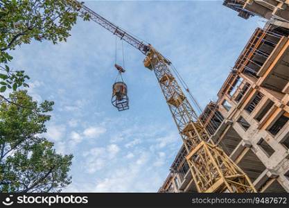 A low angle shot of a crane with equipment on a construction site with a new building infrastructure. Pouring concrete into a mold. Low angle shot of a crane with equipment on a construction site with a new building infrastructure