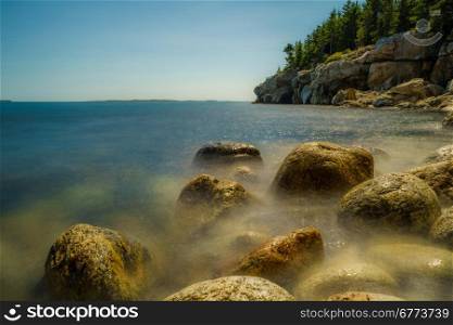 A low mist on the rugged rocks of a Maine coatline.