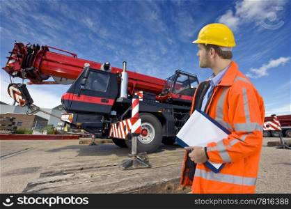 A maintenance engineer overlooking a huge mobile crane, the object of his inspection