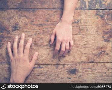 A male and a female hand on a wooden table