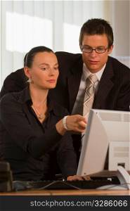 A male and female office worker looking together at a computer monitor