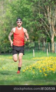 A male athlete with a tattoo on his right arm during a trail training run in the spring meadow