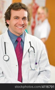 A male consultant smiles with a nurse stands out of focus in the background