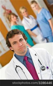 A male consultant with other medical staff out of focus in the background