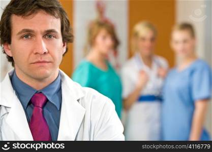 A male consultant with other medical staff out of focus in the background
