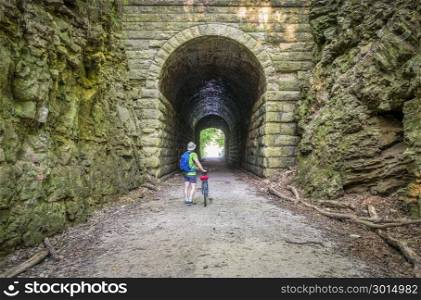 a male cyclist at MKT tunnel on Katy Trail near Rocheport, Missouri. The Katy Trail is 237 mile bike trail stretching across most of the state of Missouri converted from an old railroad.
