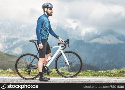A male cyclist on his bicycle on a mountain road observes the route he has to take