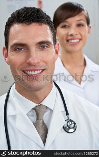 A male doctor with his female nursing colleague out of focus behind him.