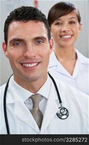 A male doctor with his female nursing colleague out of focus behind him.