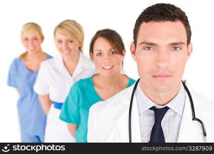 A male doctor with his team of colleagues out of focus behind him.