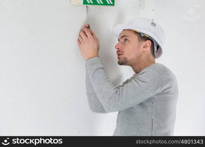 a male electrician fixing electric sign on the ceiling
