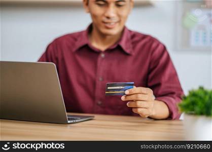 A male employee uses a credit card to pay for goods through a computer.