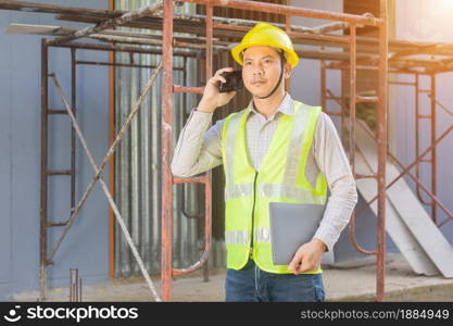 A male engineer looks at the floor plan at the construction site.