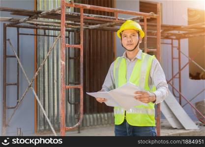 A male engineer looks at the floor plan at the construction site.