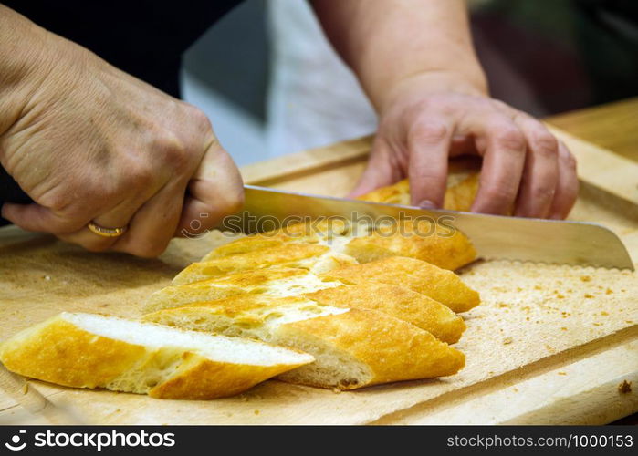 a male hand is cutting a loaf of bread on a wooden Board.. a male hand is cutting a loaf of bread on a wooden Board