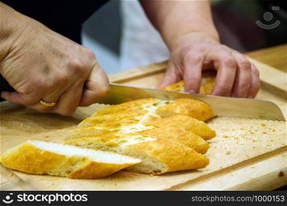 a male hand is cutting a loaf of bread on a wooden Board.. a male hand is cutting a loaf of bread on a wooden Board