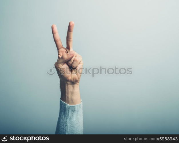 A male hand is displaying the v for victory sign