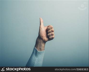 A male hand is displaying thumbs up